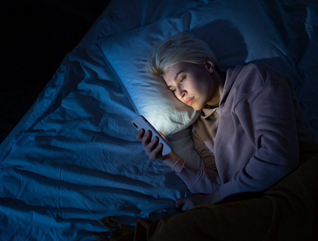 Girl lying on the pillow in the dark and looking to the phone screen