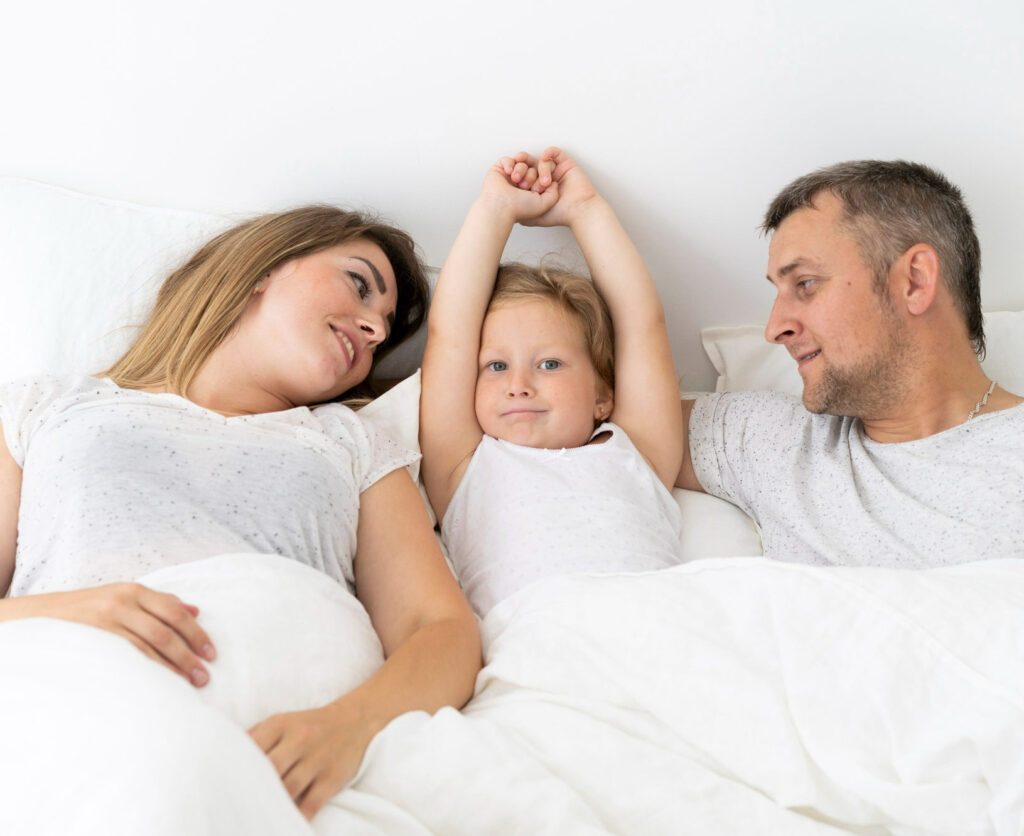 Two parents with little girl in the middle is lying in bed